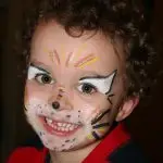 Portrait eines kleinen glücklichen Jungens, als Tiger geschminkt, strahlendes Lachen mit Zahnlücke